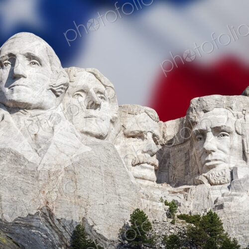 The presidential carvings of Mount Rushmore stand before a soft focus American flag in… The presidential carvings of Mount Rushmore stand before a soft focus American flag in…