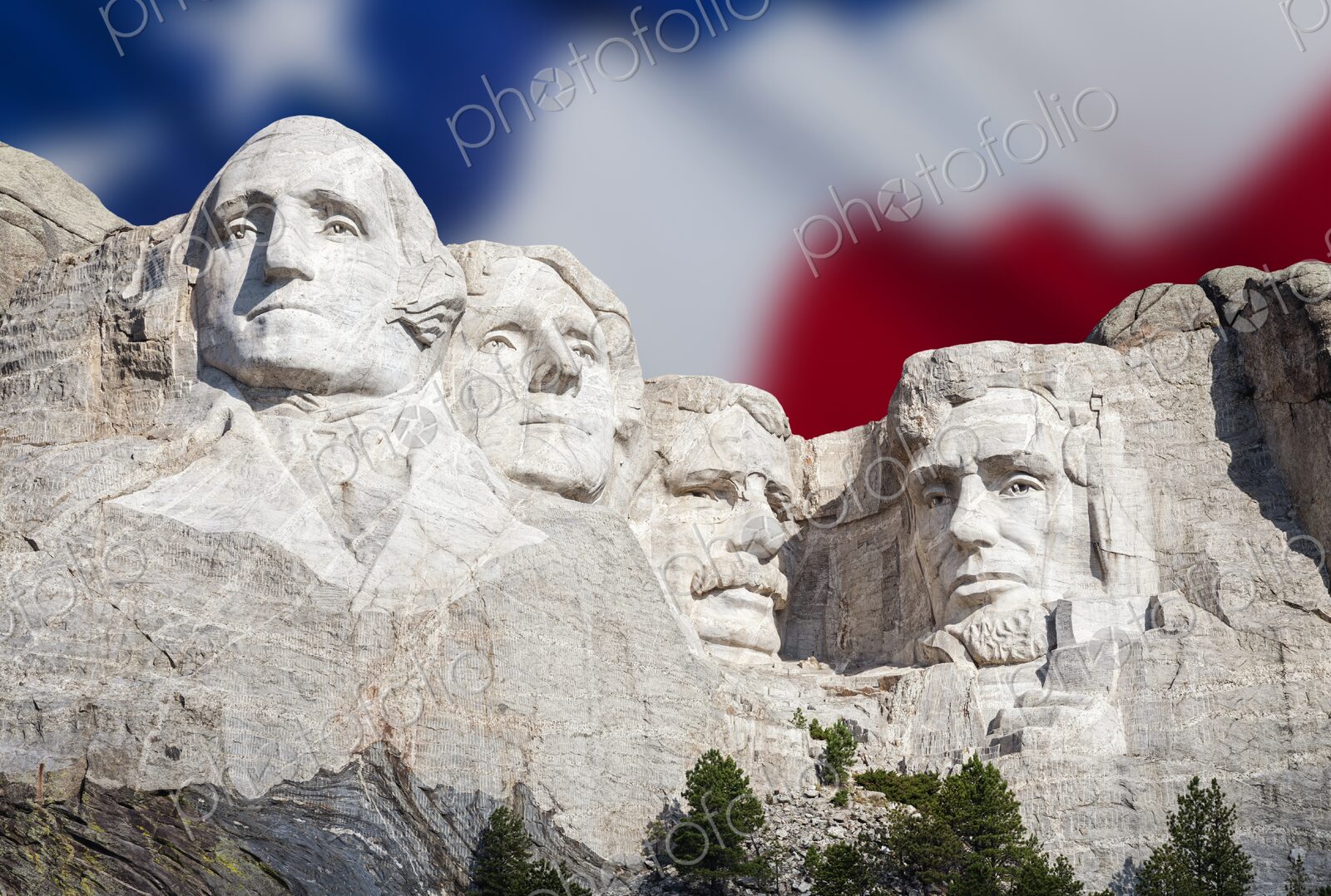The presidential carvings of Mount Rushmore stand before a soft focus American flag in…