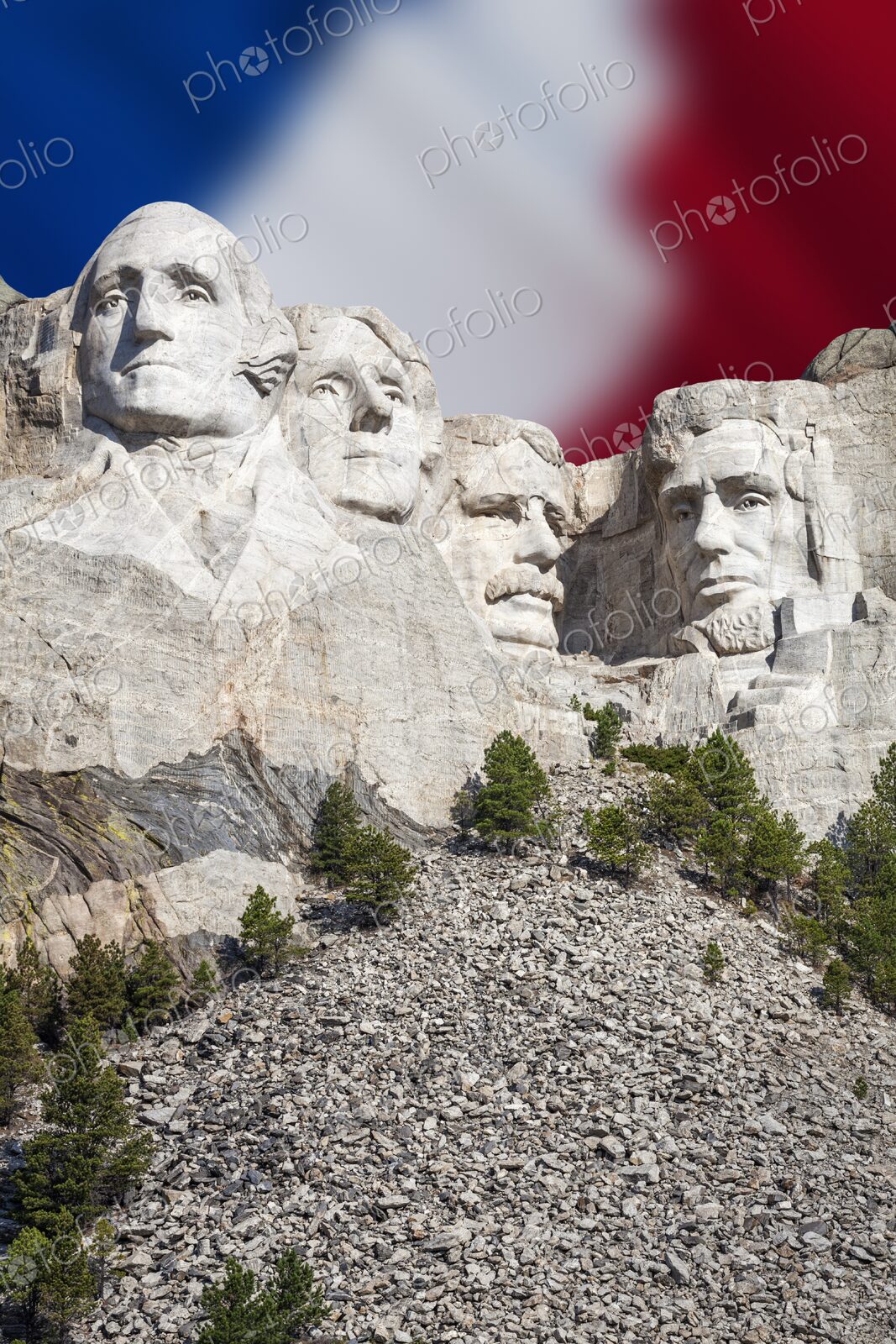 The presidential carvings of Mount Rushmore stand before a soft focus American flag in…