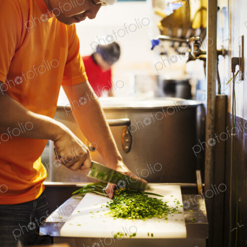 The ramen noodle shop. A chef chopping vegetables.