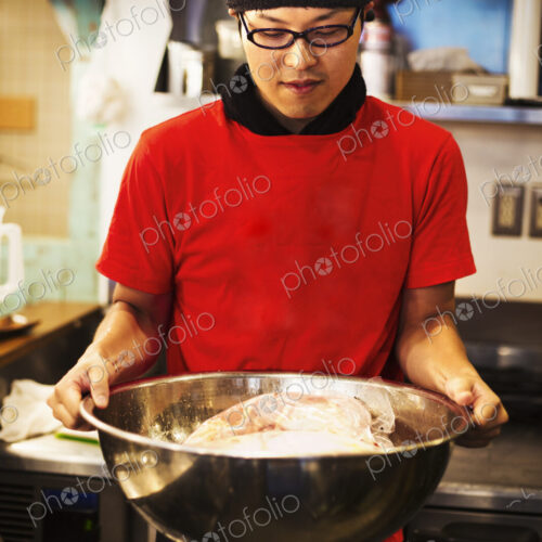 The ramen noodle shop. A chef preparing a huge metal bowl of broth with meat ingredients.