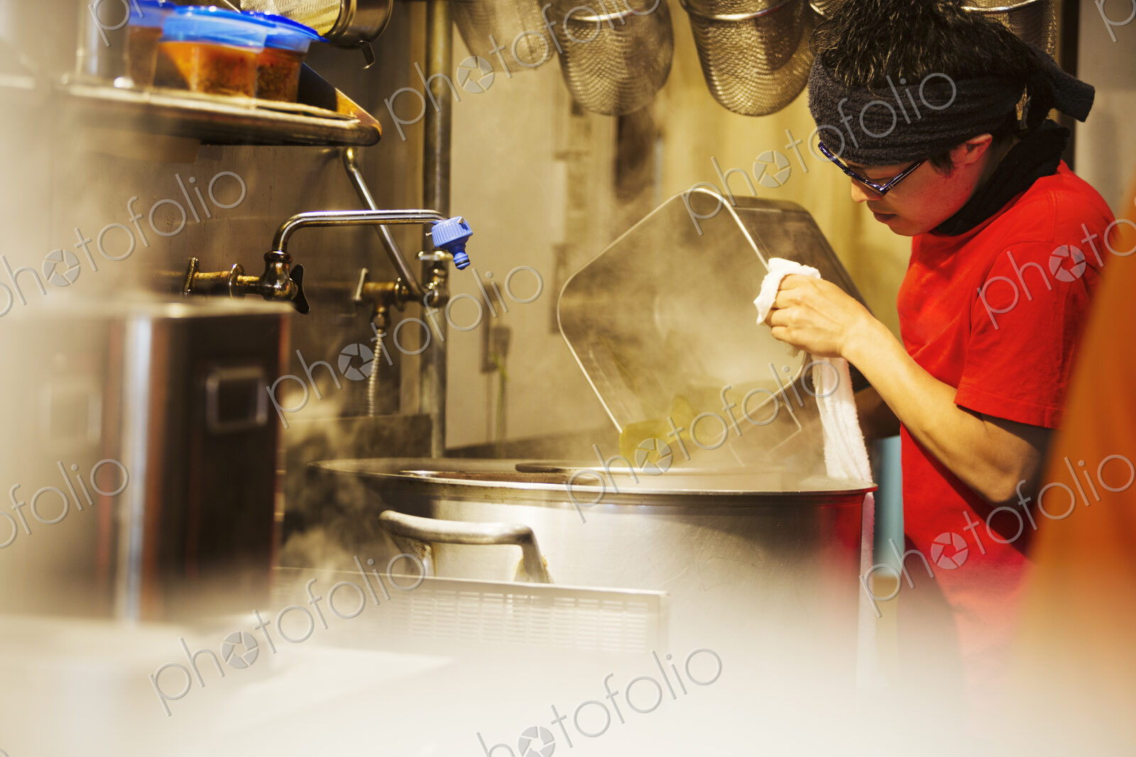 The ramen noodle shop. A chef working in a kitchen preparing food using a stove and…
