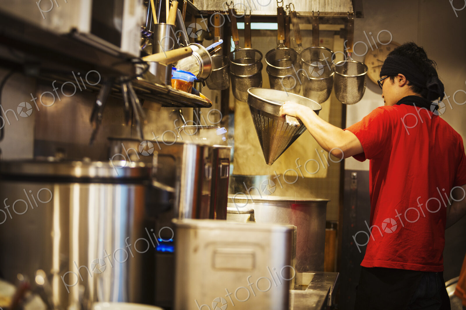 The ramen noodle shop. A chef working in a kitchen preparing food using a stove and…