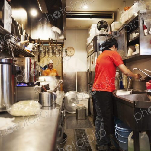 The ramen noodle shop. A chef working in a kitchen preparing food using a stove and…