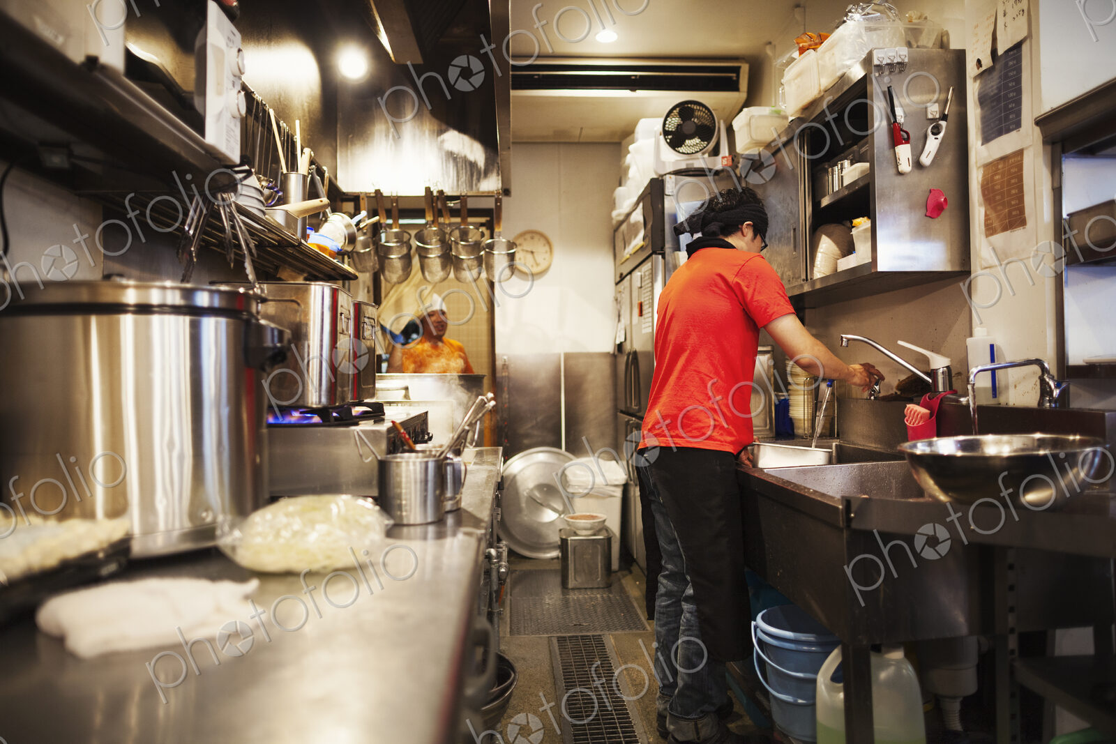 The ramen noodle shop. A chef working in a kitchen preparing food using a stove and…