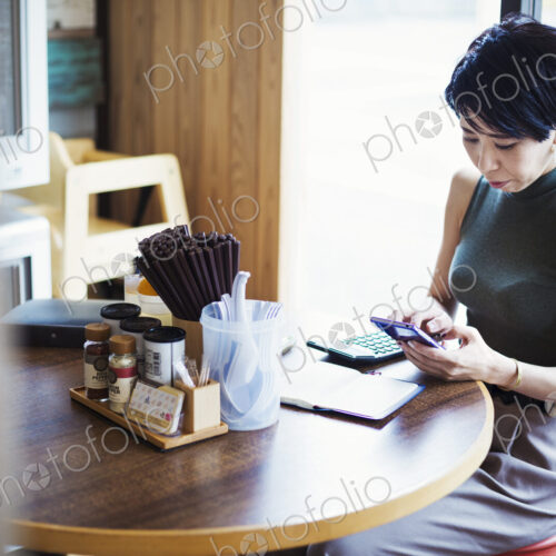 The ramen noodle shop. A woman sitting at a table using her smart phone. The ramen noodle shop. A woman sitting at a table using her smart phone.