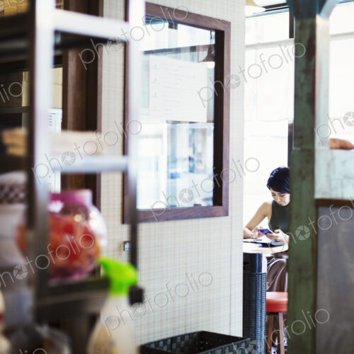 The ramen noodle shop. A woman sitting in a cafe, view through a door. The ramen noodle shop. A woman sitting in a cafe, view through a door.
