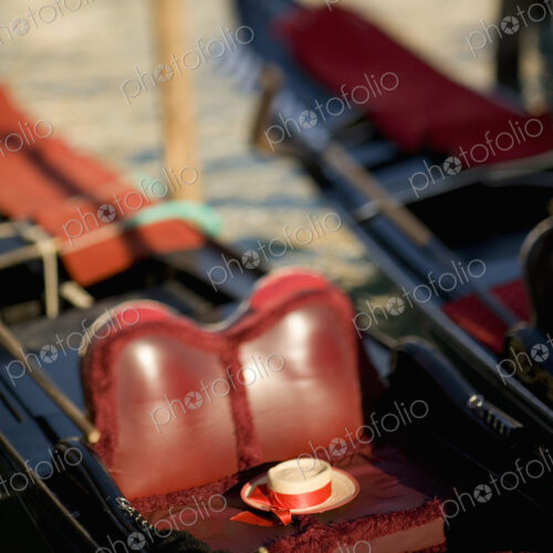 The red leather seat of a traditional gondola boat, and a straw boater with a ribbons… The red leather seat of a traditional gondola boat, and a straw boater with a ribbons…