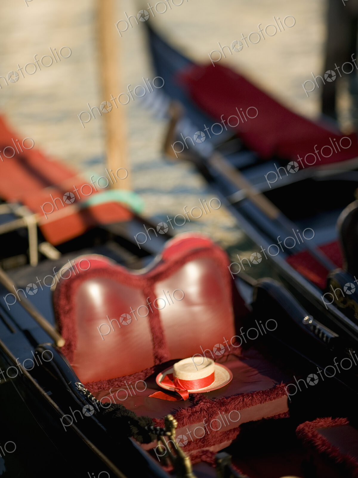 The red leather seat of a traditional gondola boat, and a straw boater with a ribbons…