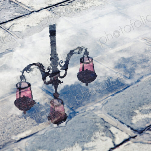 The reflection of an ornate street lamp in a puddle on a rainy day in Venice, Italy. The reflection of an ornate street lamp in a puddle on a rainy day in Venice, Italy.
