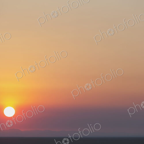 The rising sun over flat desert landscape at dawn in Nevada.
