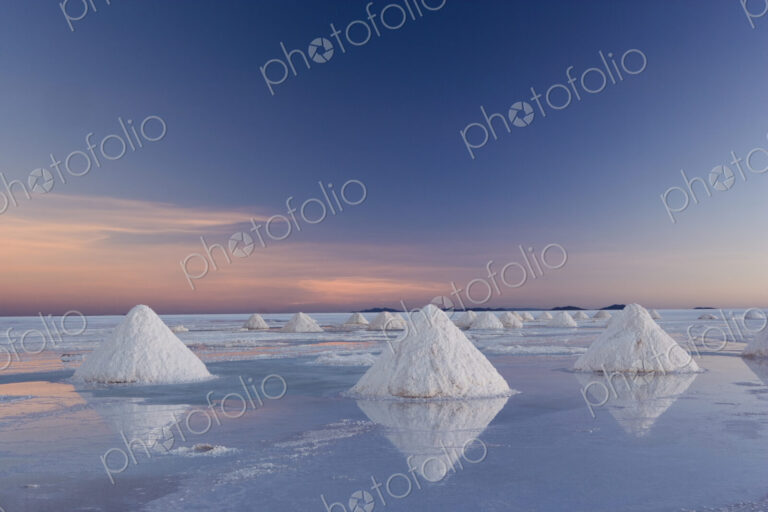 The salt pans of Salar de Uyuni, with shallow water and mineral deposits. White salt…