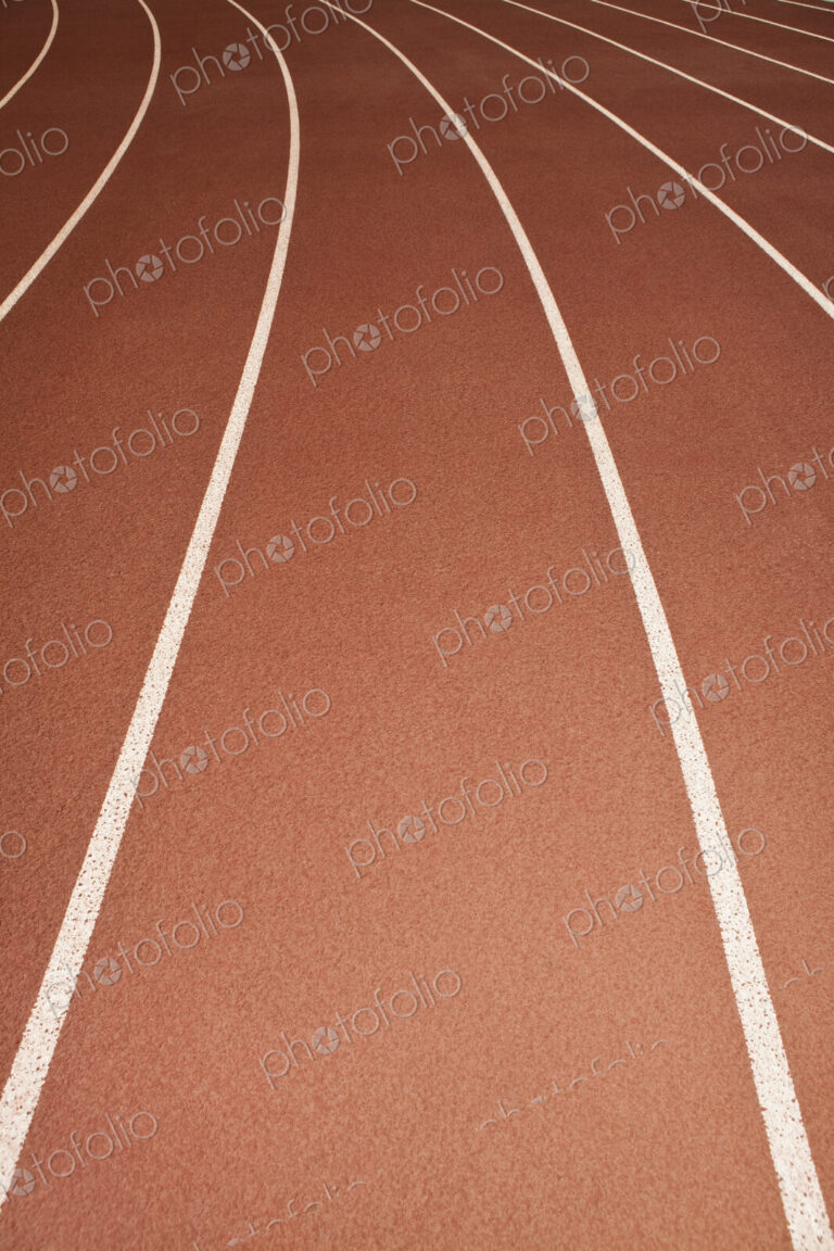 The surface of a sports athletics running track, red surface with white painted lane…