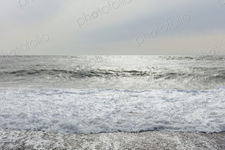The surface of the ocean and waves, moody overcast sky above
