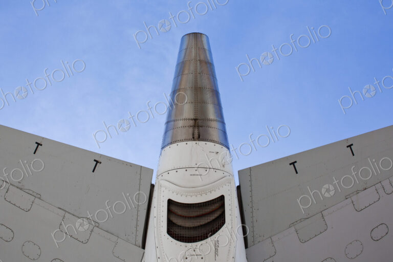 The underside of an aircraft, wings and mesh covered exhaust outlet.