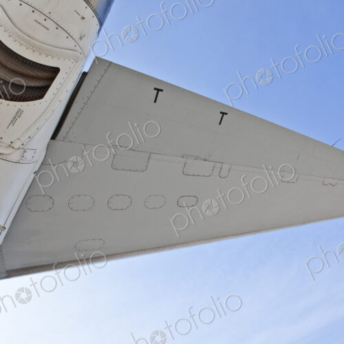 The underside of an aircraft, wings and mesh covered exhaust outlet.