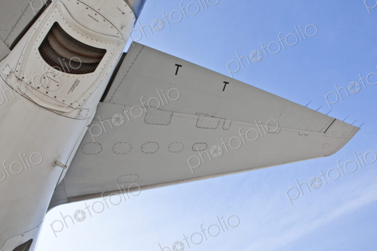 The underside of an aircraft, wings and mesh covered exhaust outlet.