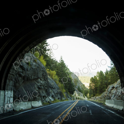 The view of the end of a road tunnel from the highway.