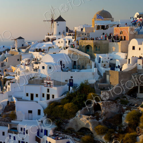The windmills of Santorini in Greece. A hilltop town of whitewashed houses. Sunset.