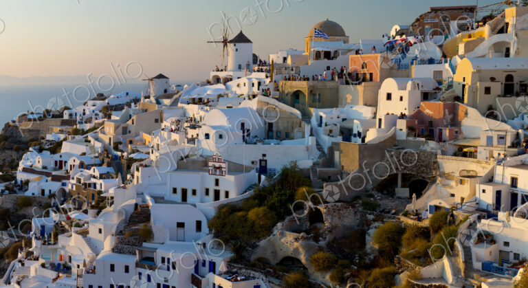 The windmills of Santorini in Greece. A hilltop town of whitewashed houses. Sunset.