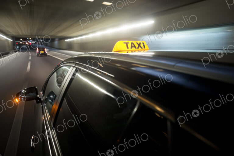 The yellow roof sign of a taxi driving through a tunnel.