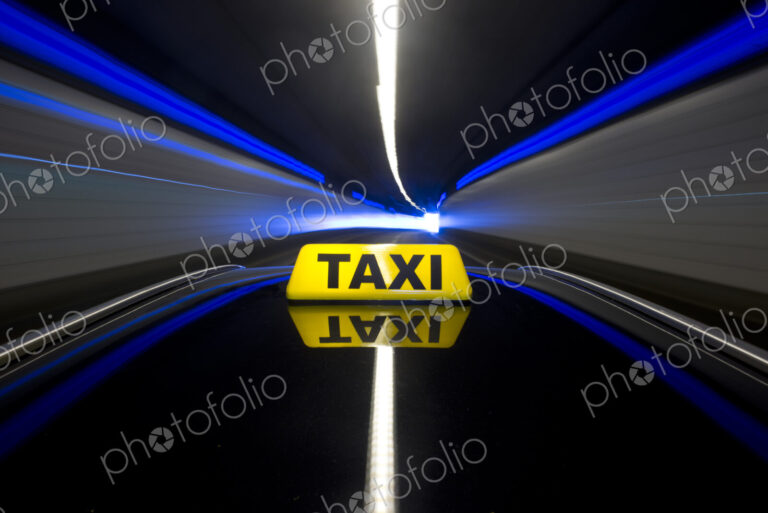 The yellow roof sign of a taxi driving through a tunnel.