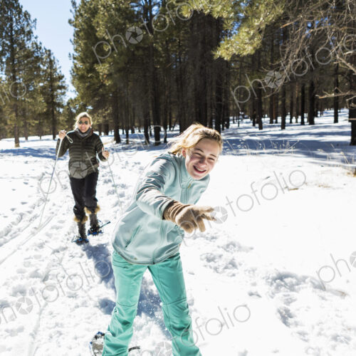 Thirteen year old girl and her mother on snow shoes on a trail in snow. Thirteen year old girl and her mother on snow shoes on a trail in snow.
