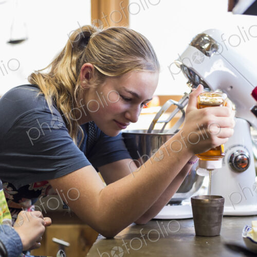 Thirteen year old teenage girl and her 6 year od brother in the kitchen,sweezing honey…