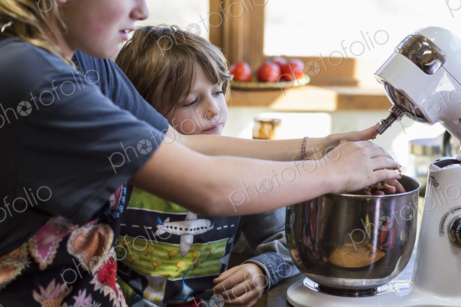 Thirteen year old teenage girl and her 6 year od brother in the kitchen,using a mixing…