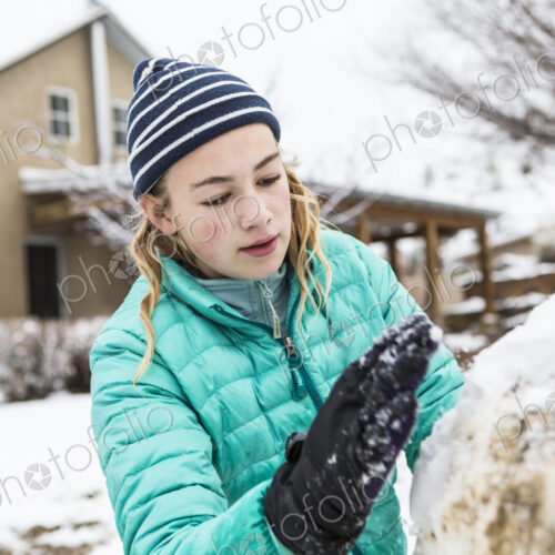 Thirteen year old teenage girl building a snowman Thirteen year old teenage girl building a snowman