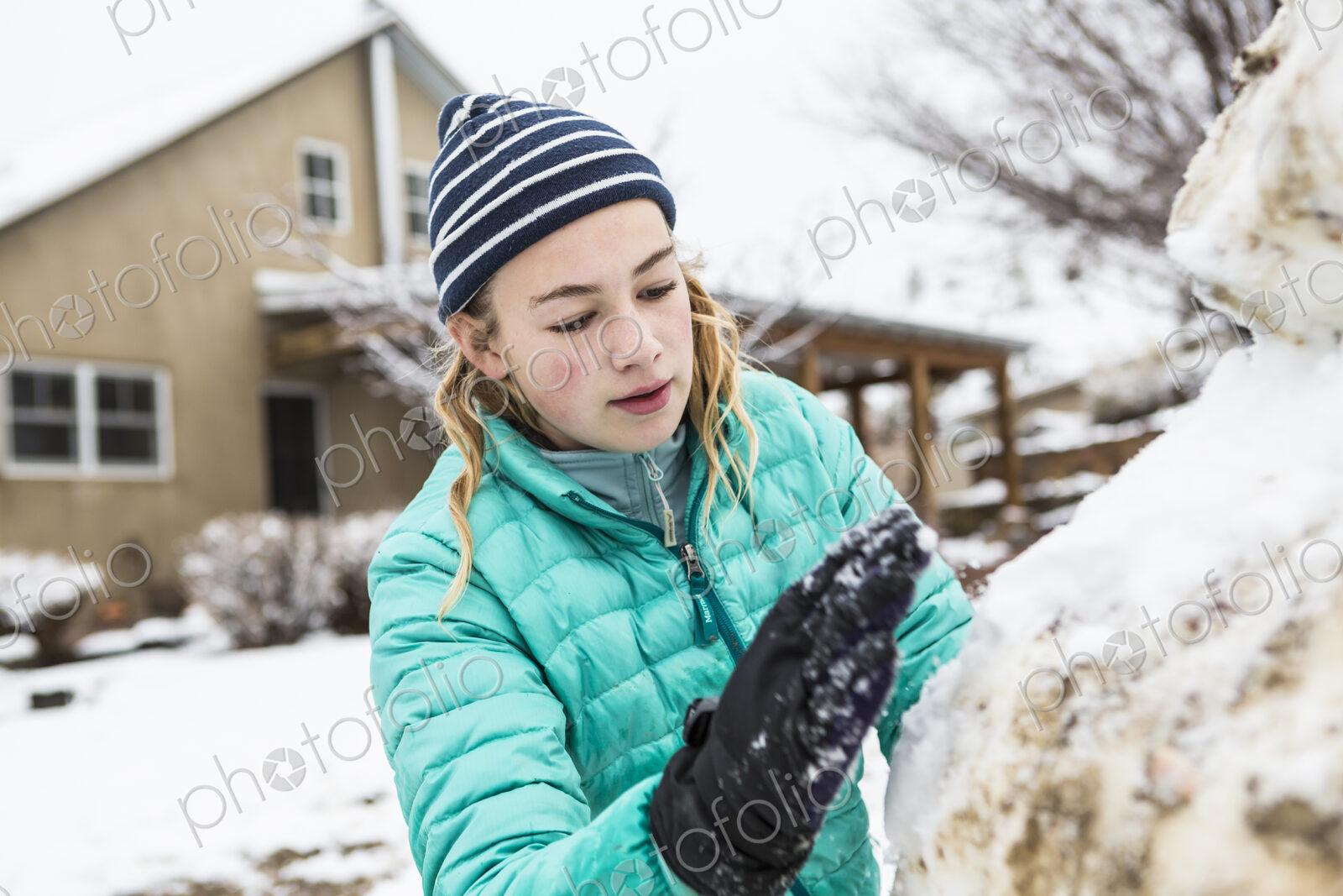 Thirteen year old teenage girl building a snowman