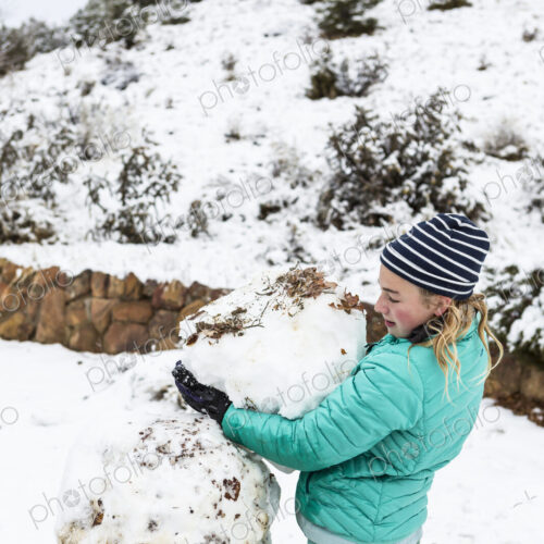 Thirteen year old teenage girl building a snowman Thirteen year old teenage girl building a snowman