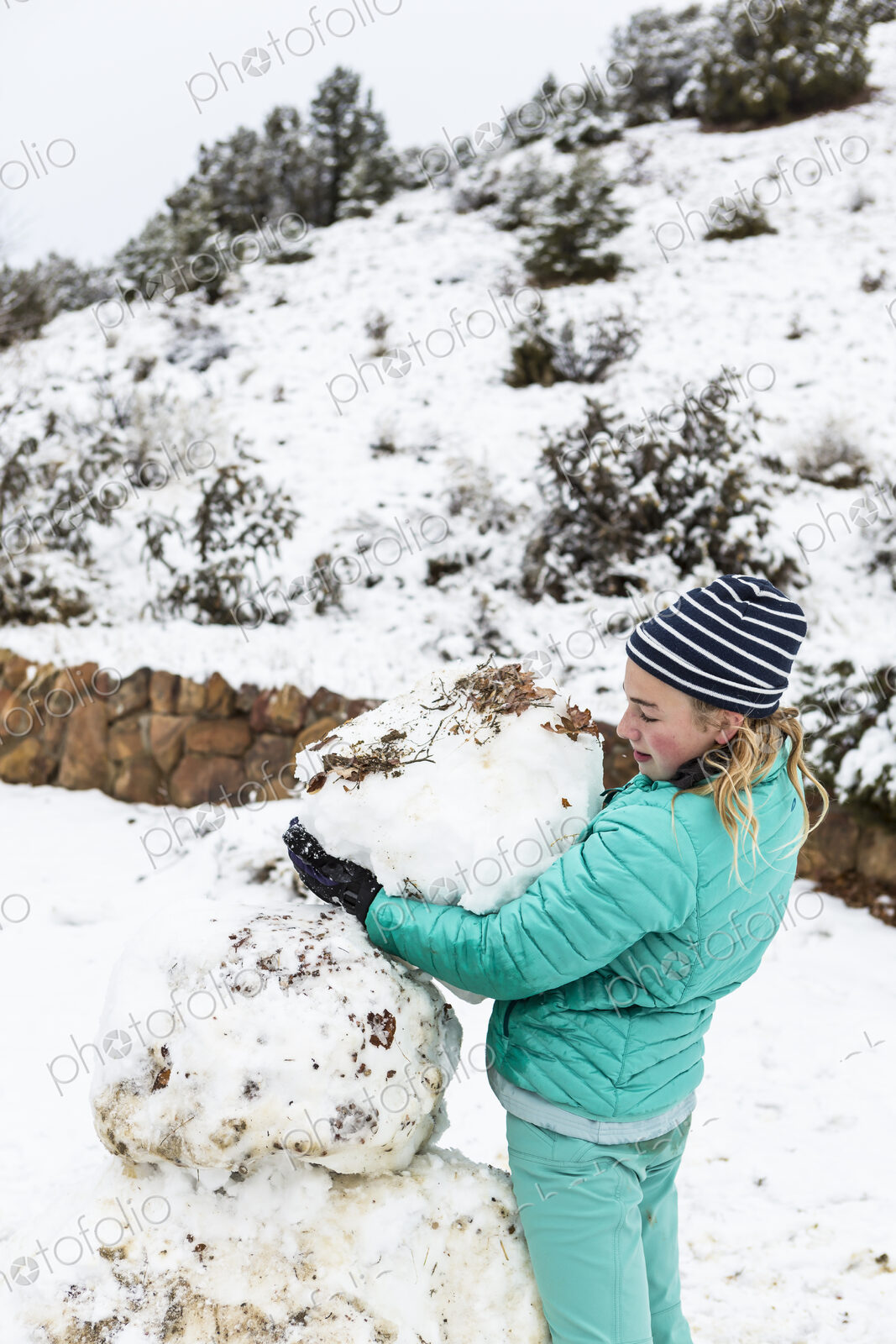 Thirteen year old teenage girl building a snowman