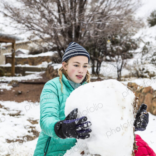Thirteen year old teenage girl building a snowman Thirteen year old teenage girl building a snowman
