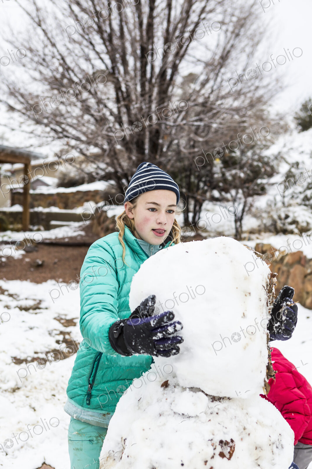 Thirteen year old teenage girl building a snowman
