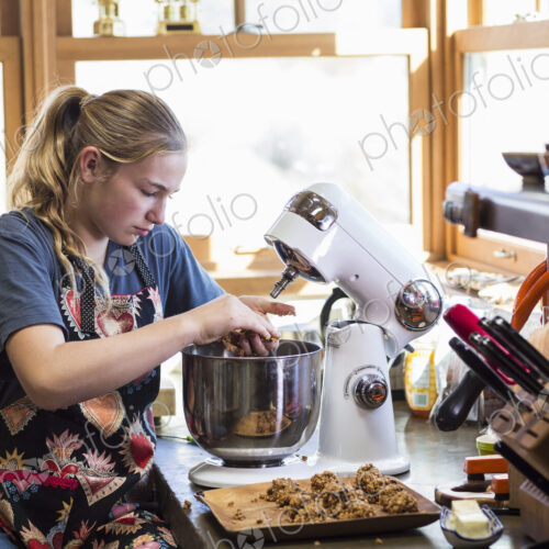 Thirteen year old teenage girl using mixer in the kitchen.