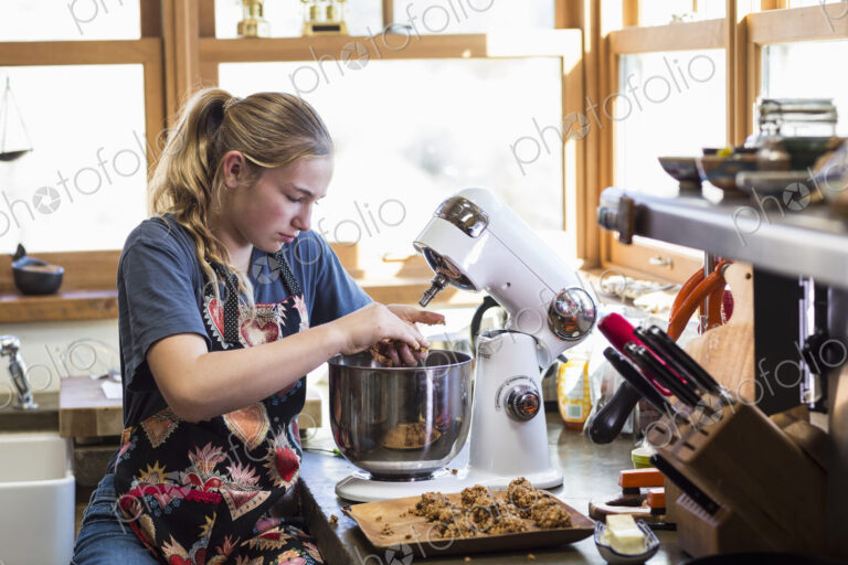 Thirteen year old teenage girl using mixer in the kitchen.
