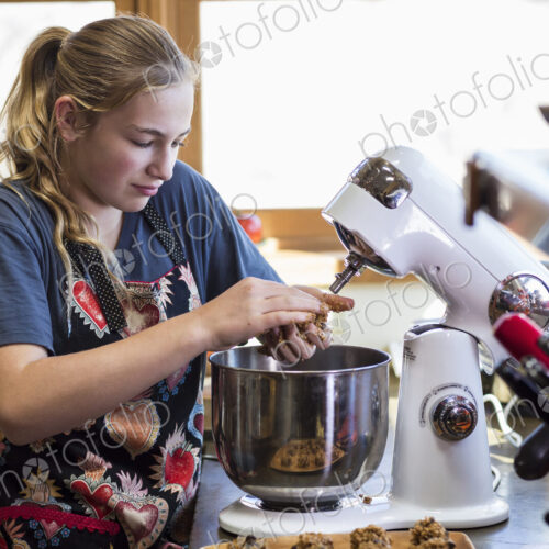 Thirteen year old teenage girl using mixer in the kitchen.