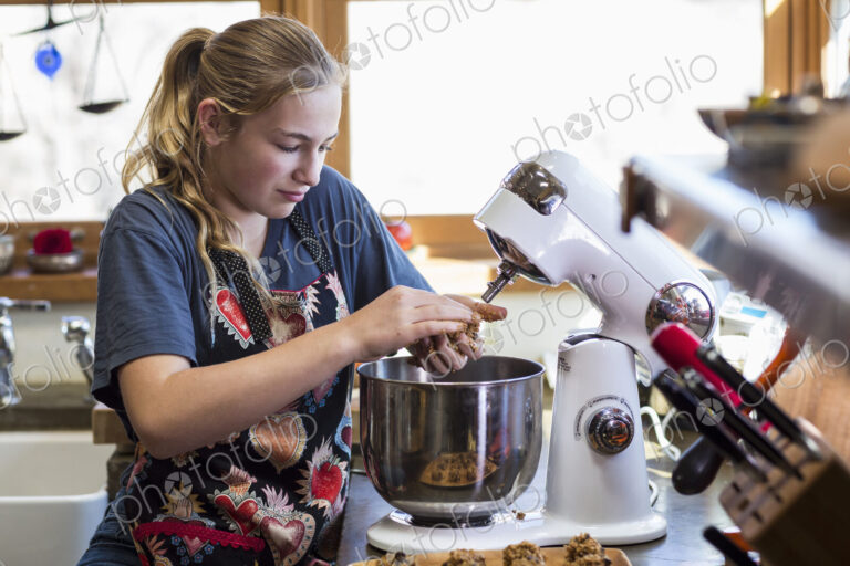 Thirteen year old teenage girl using mixer in the kitchen.