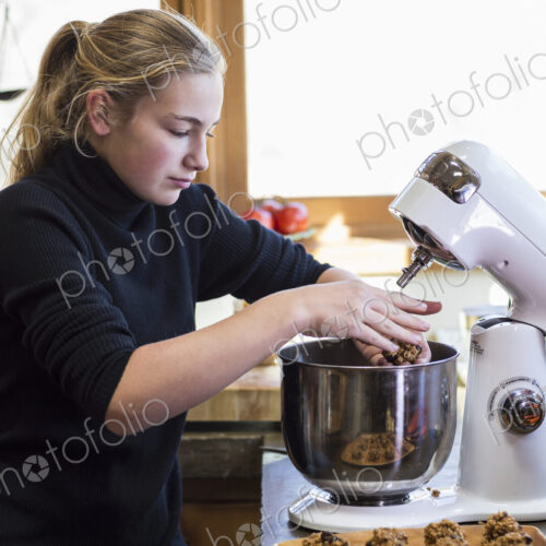 Thirteen year old teenage girl using mixer in the kitchen.