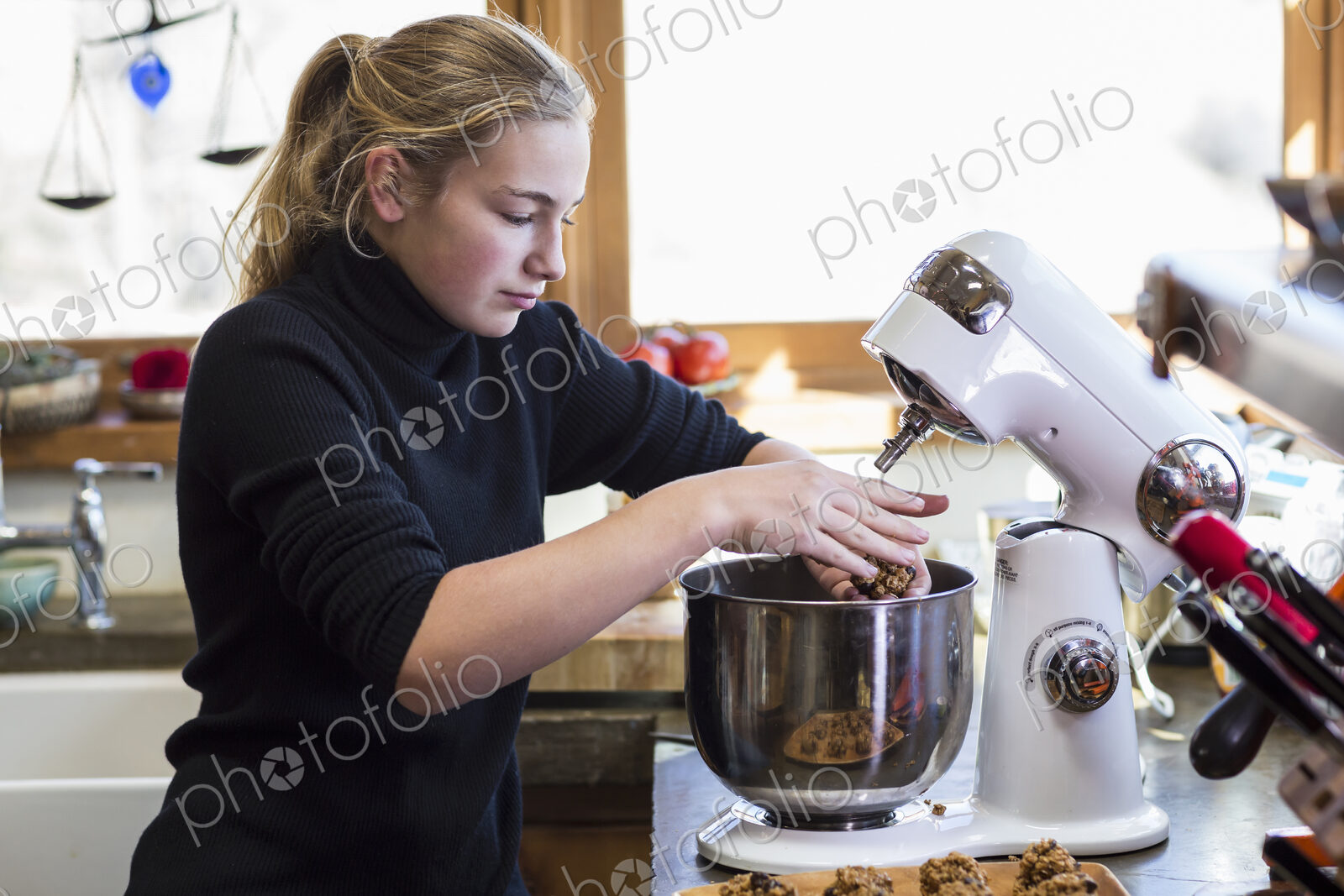 Thirteen year old teenage girl using mixer in the kitchen.