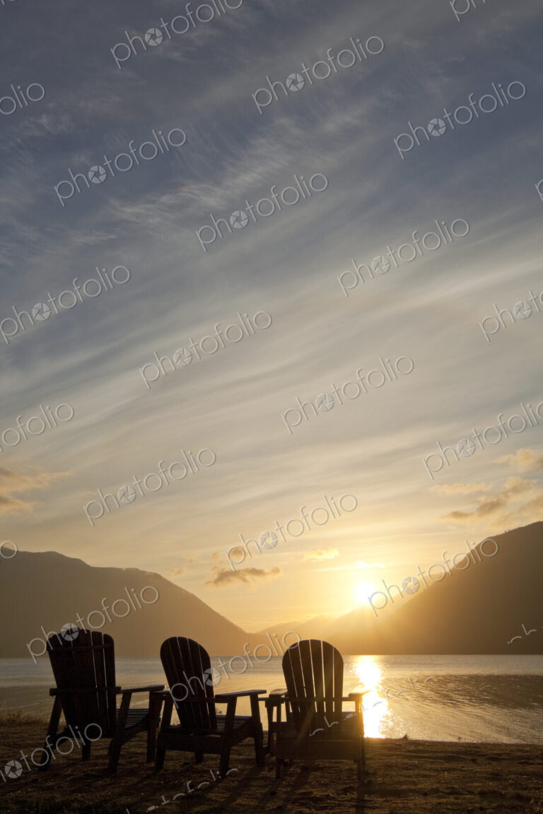 Three Adirondack style wooden lounge chairs at Crescent Lake Lodge at Olympic National…