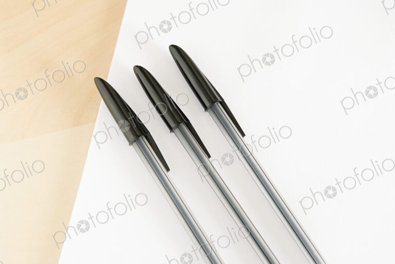 Three ball point pens lined up in a row on a white background.