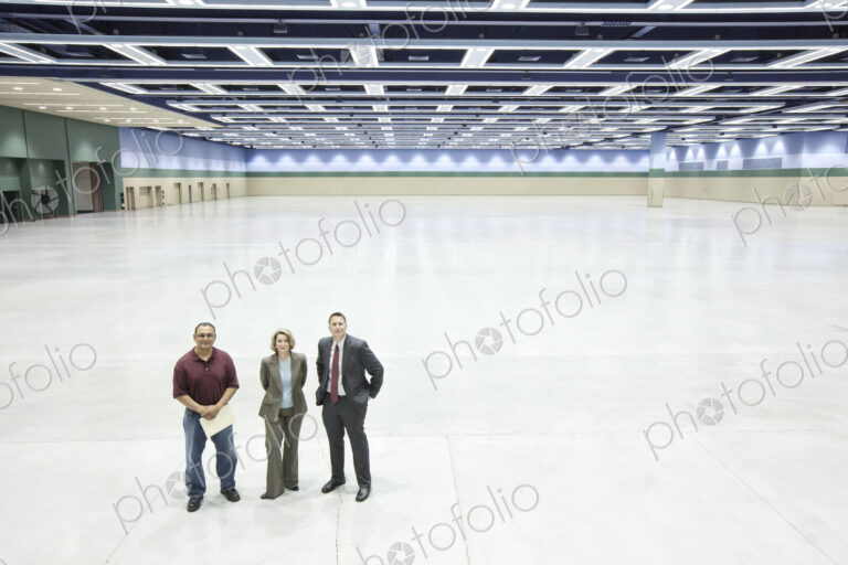 Three business meeting planners standing in the middle of a convention center arena.