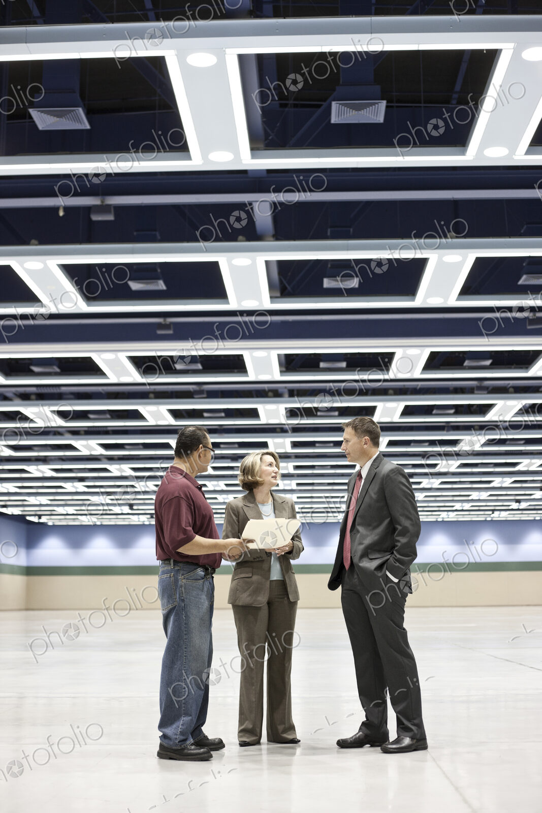 Three business meeting planners talking on the floor of a covnention center space.