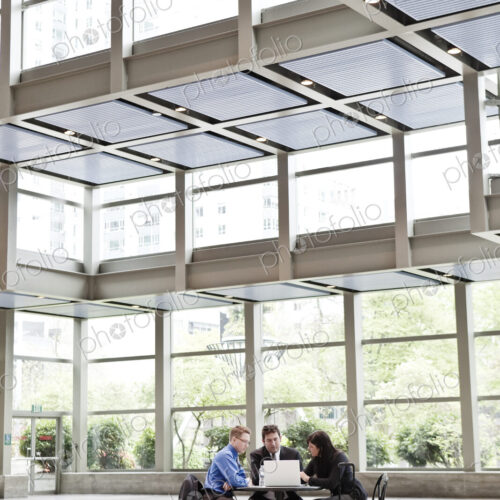 Three business people having a meeting at a table in a convention center lobby. Three business people having a meeting at a table in a convention center lobby.