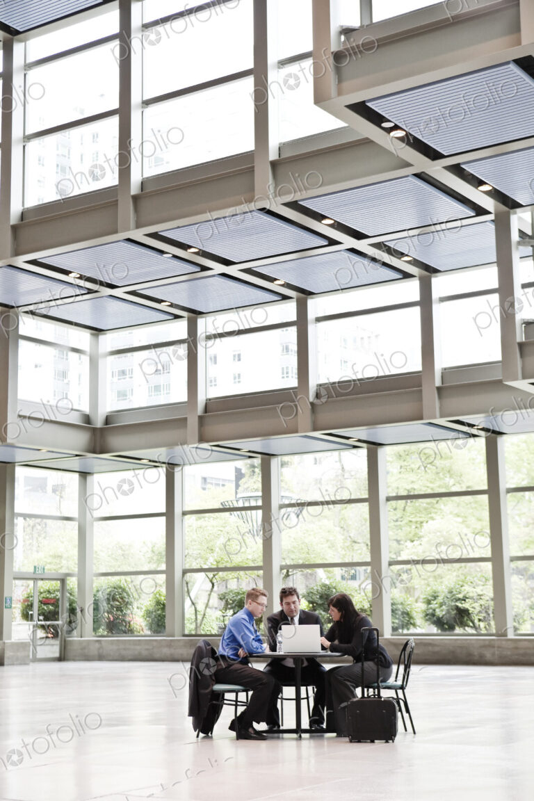 Three business people having a meeting at a table in a convention center lobby.
