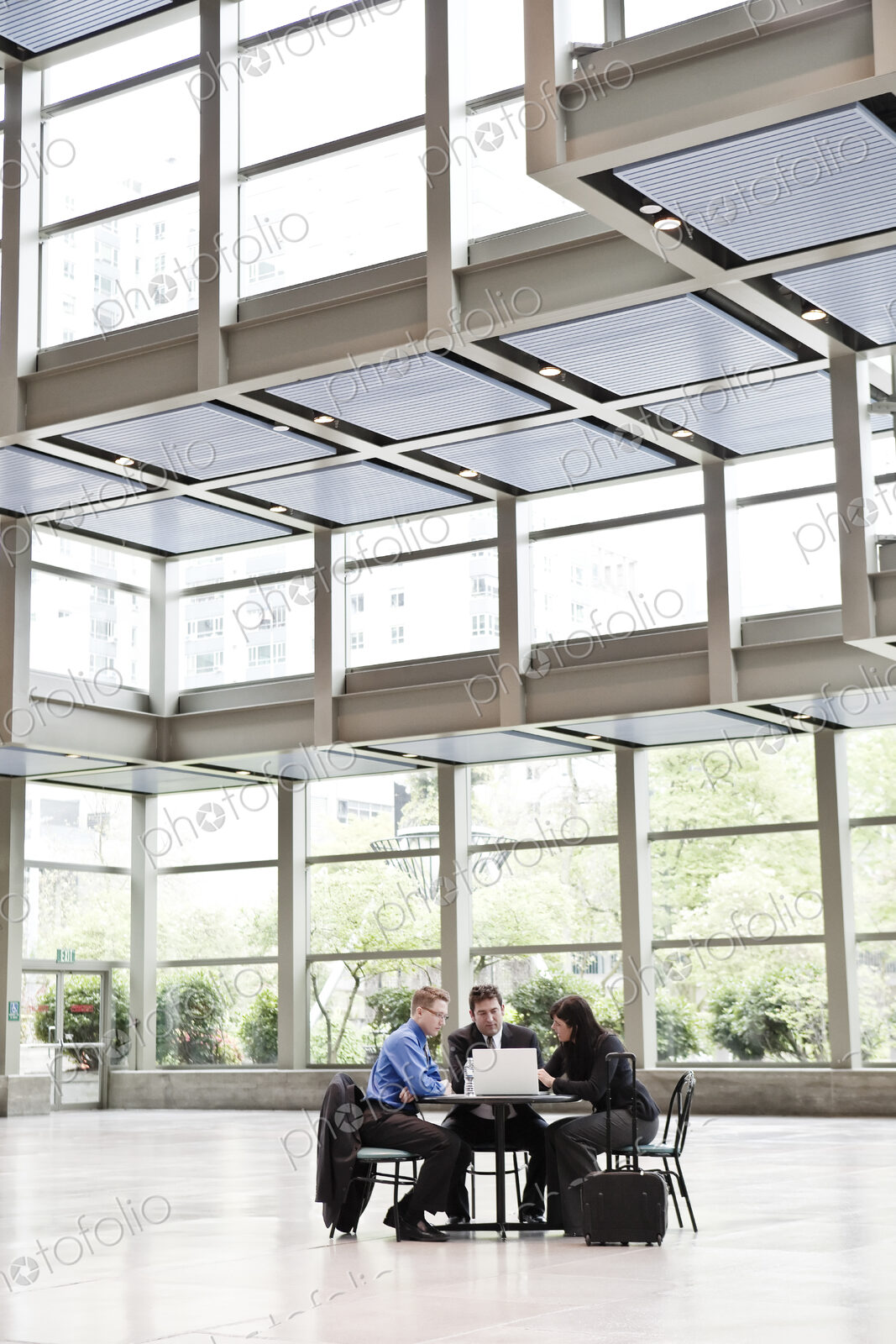 Three business people having a meeting at a table in a convention center lobby.