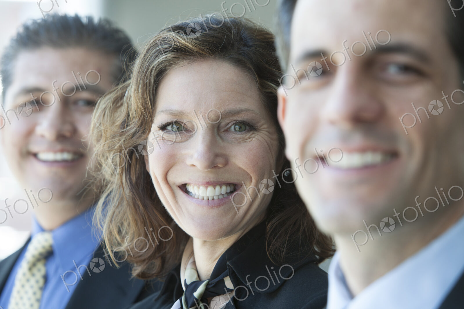 Three business people, head and shoulders, looking at camera portrait.