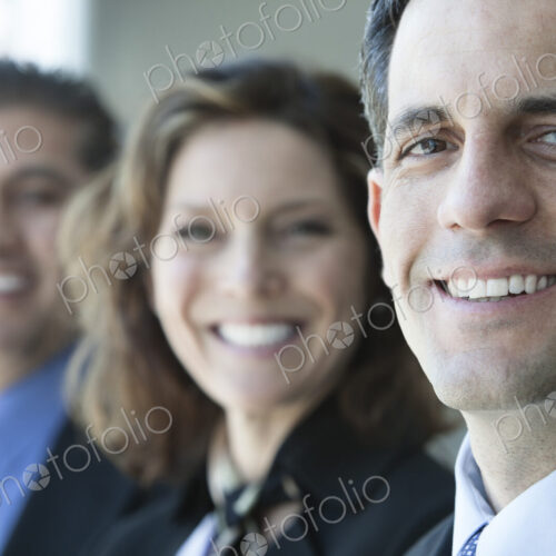 Three business people, head and shoulders, looking at camera portrait.